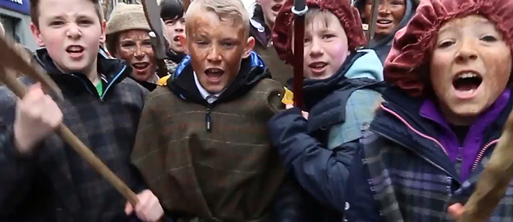 Children with fake weapons charging in historical reenactment at the Border reviews Festival in Hawick Scotland