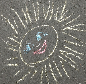 chalked picture on the road of a smiley sun  