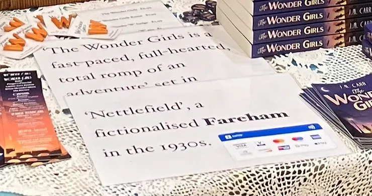close up of my market stall showing the sign I use to catch readers' attention. The sign reads ''The Wonder Girls is a fast-paced, full-hearted romp of an adventure'  set in a fictionalised  Fareham in the 1930s.'