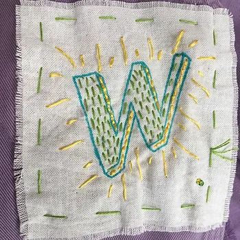A letter w embroidered on a small piece of cloth to make a badge,
