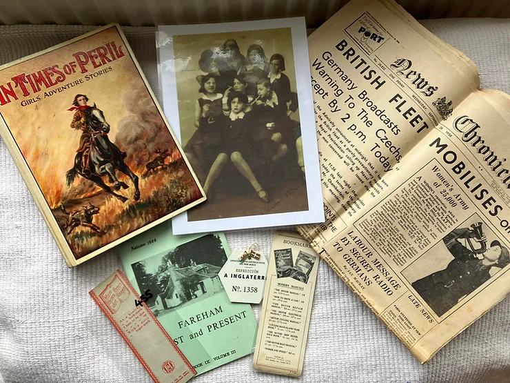 A photo of an antique (1930s) book of girls adventure stories, the girl gang picture that inspired the series, a 1938 newspaper, some antique book marks, a replica hexagonal badge worn by the Spanish child refugees (bk2), and a local history journal from 1988 for Fareham